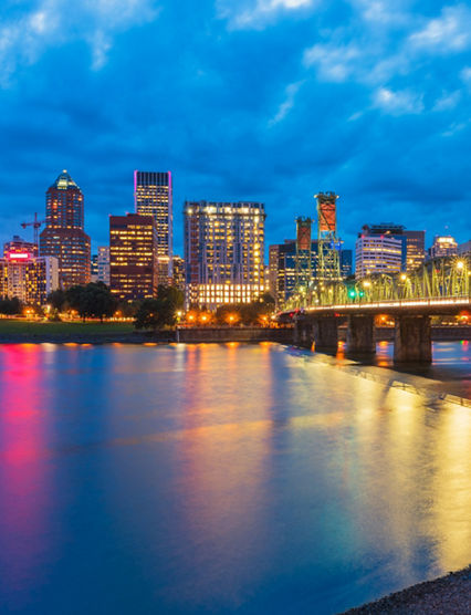 Skyline of Portland, Oregon, USA at dusk, with Willamette River and Hawthorne Bridge.