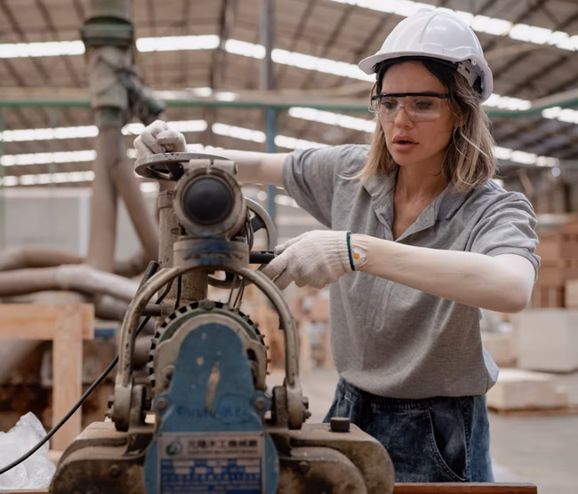 Confident female worker standing in lumber warehouse of hardwood furniture factory inspecting production machine. Serious female technician or engineer busy working with tool in woodwork manufacturing