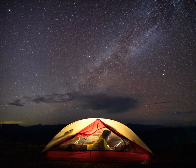 Asian female camping at night with under the Milky Way on the top of a mountain.