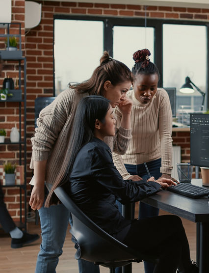 Mixed team of software engineers brainstorming ideas for new code library in front of computer screens compiling algorithms. Diverse app developers collaborating on group project in it agency office.