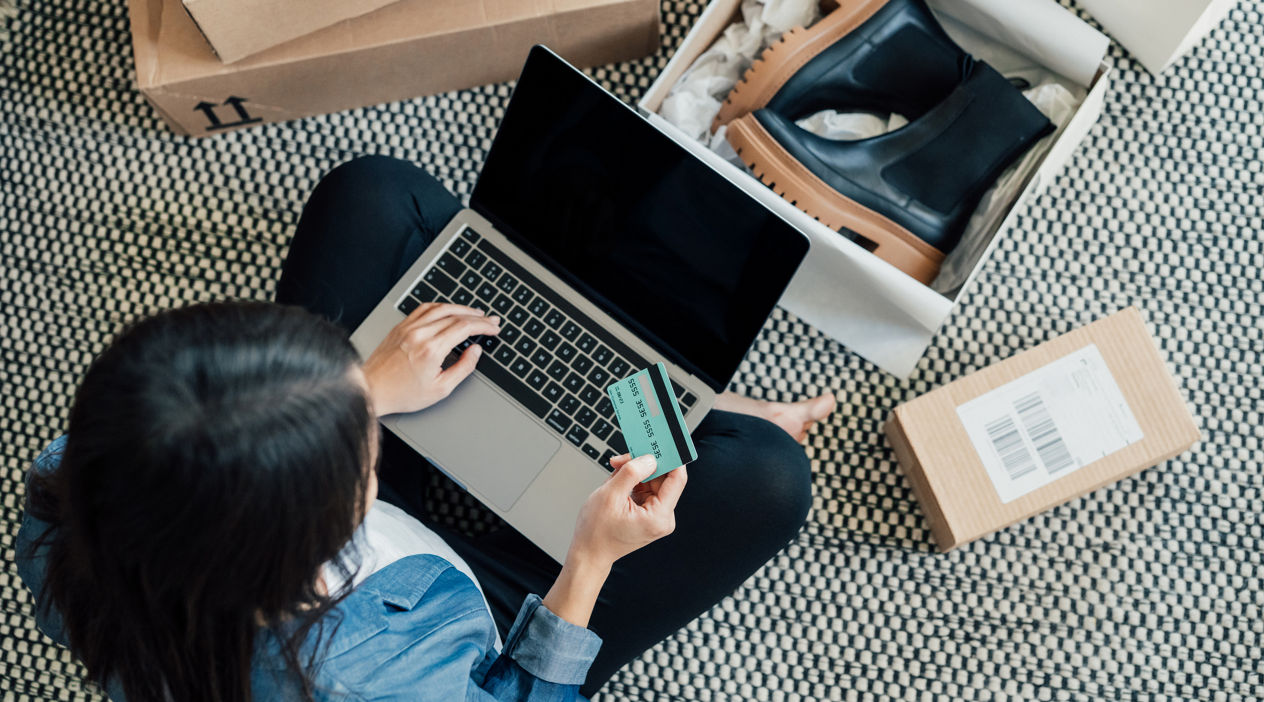 High angle view of a young Asian woman shopping online on laptop, making payment with credit card. Enjoying Seasonal sales. Shopaholic concept.