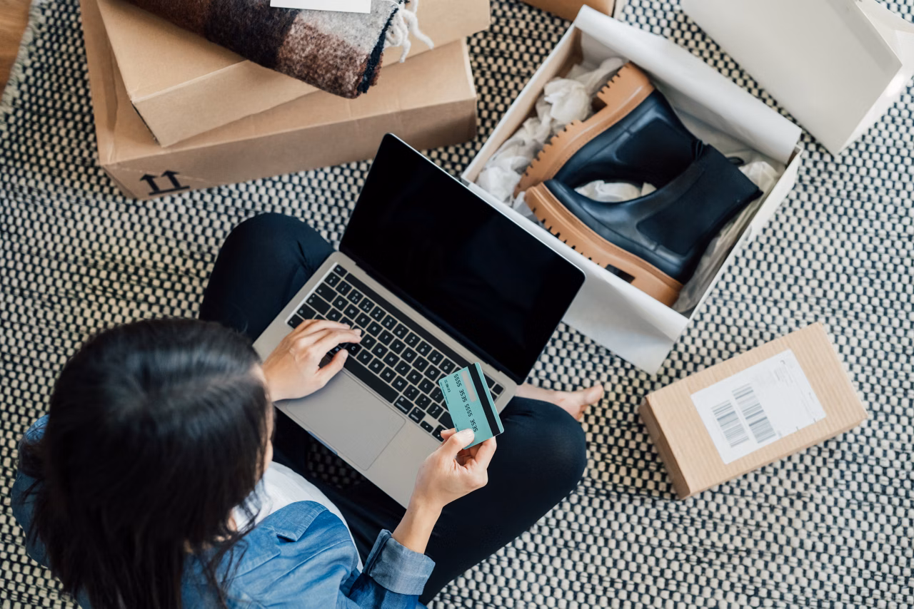 High angle view of a young Asian woman shopping online on laptop, making payment with credit card. Enjoying Seasonal sales. Shopaholic concept.