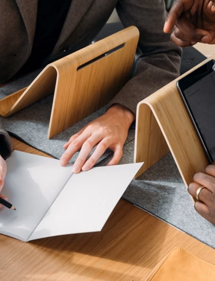 two people working on tablets with a notebook in front of them