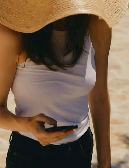 Woman wearing a hat and using a smartphone outdoors