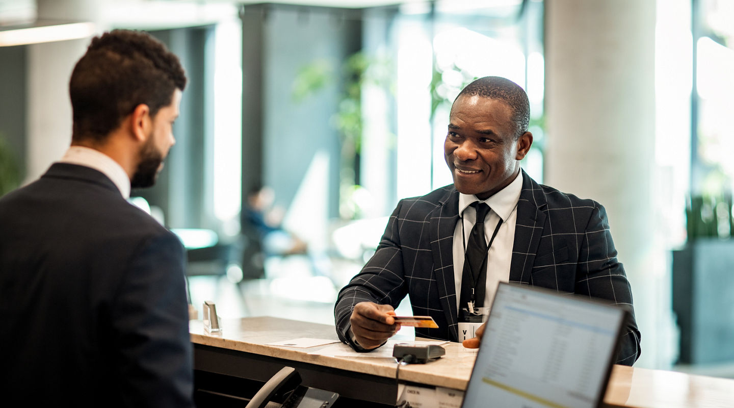 Businessman paying stay at hotel with credit card at reception