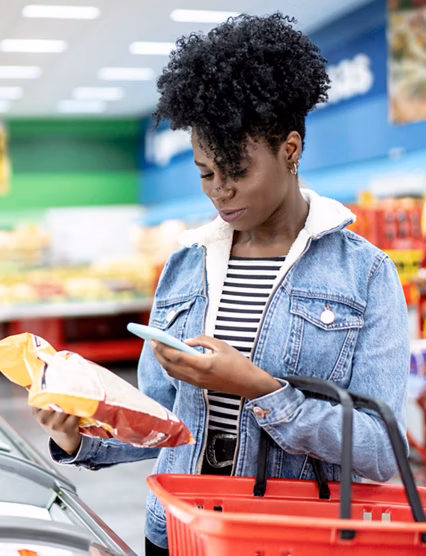 Woman is shopping in supermarket and scanning barcode with smartphone