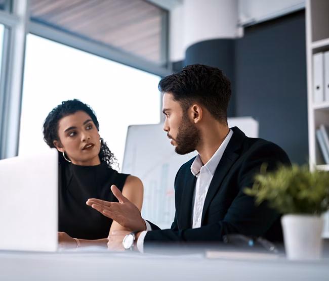 Serious, business meeting and people with laptop for performance review, communication and feedback. Corporate team, man and woman with computer in office for discussion and collaboration on project.