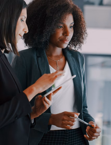 Shot of two young businesswomen using an interactive whiteboard to analyse data in a modern office