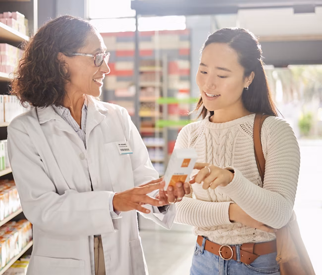 Asian woman, medicine shopping or pharmacist in pharmacy for retail healthcare product information. Women or friendly doctor helping a customer with store medication advice, pills or medical drugs.