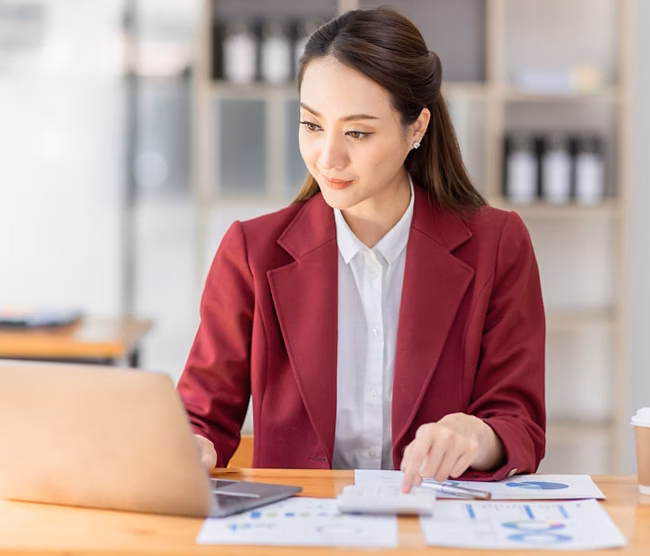 Asian woman working laptop in workplace, Business woman wearing red jacket suit busy working on laptop computer checking finances, investment, economy, saving money or insurance concept
