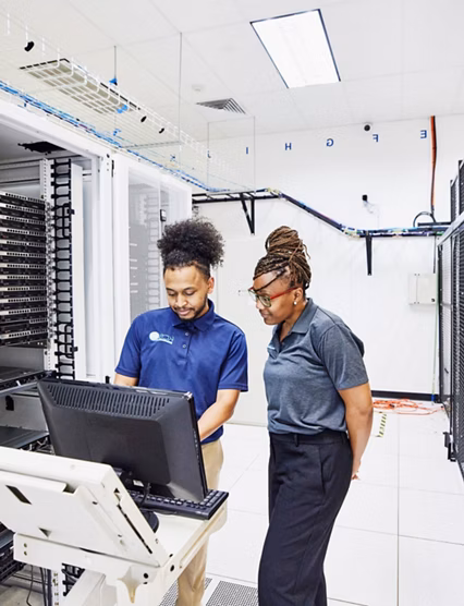 Medium wide shot of IT professionals in discussion while configuring server in data center