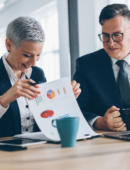 Businessman and business woman working together at the office using laptop and documents