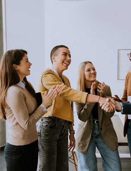 Memembers of young creative team shaking hands while working in the modern office