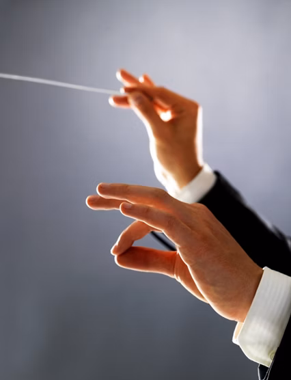 Cropped image of a male orchestra conductor directing with his baton in concert