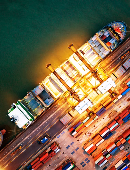 Top view of international port with Crane loading containers in import export business logistics at night.