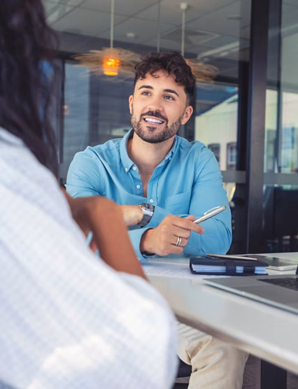 Business colleagues having a conversation. They are discussing a charts and graphs on a laptop computer. They are both young business people casually dressed in an office. Could be an interview or consultant working with a client.