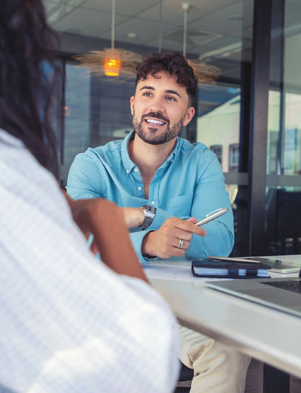 Business colleagues having a conversation. They are discussing a charts and graphs on a laptop computer. They are both young business people casually dressed in an office. Could be an interview or consultant working with a client.