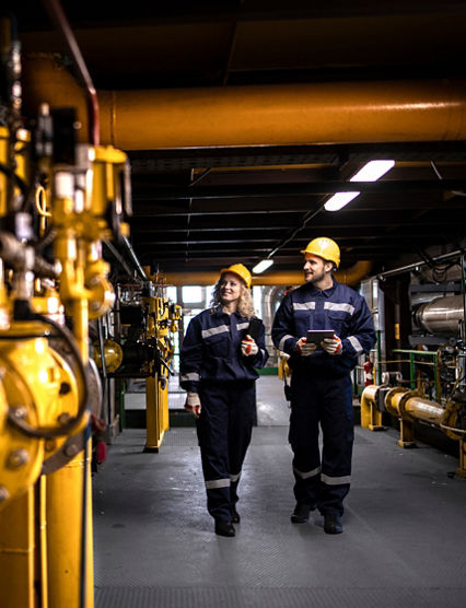 Industrial workers controlling production of natural gas and distribution in refinery.