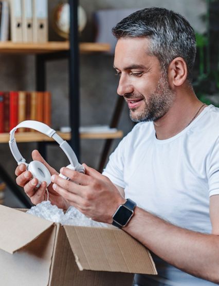 Joyful middle aged man get his delivery with heaphones at home