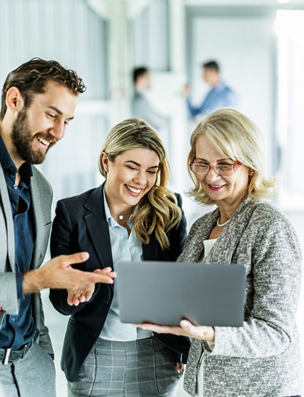 Young happy business colleagues and their mature manager working on a computer in the office.