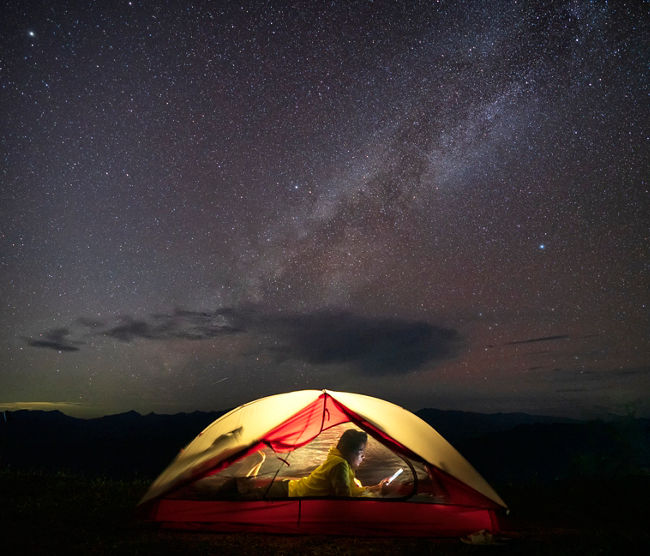 Asian female camping at night with under the Milky Way on the top of a mountain.