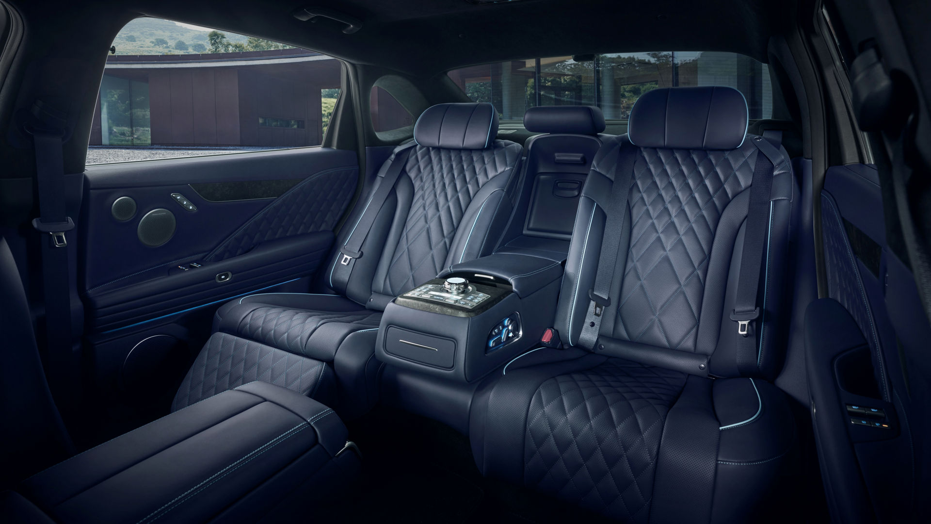 View of the back seat inside the Electrified G80. The quilted seats in a luxurious ecru black monotone and the controller in the center are visible.