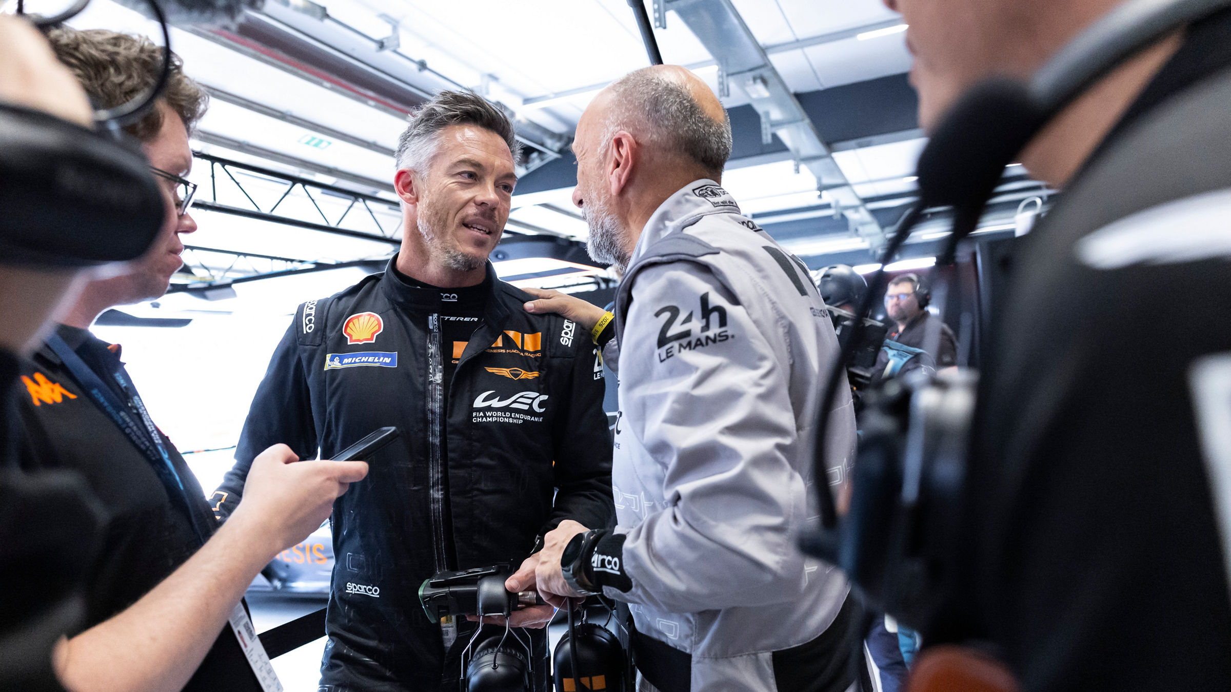 André Lotterer talking inside pit garage with crew.