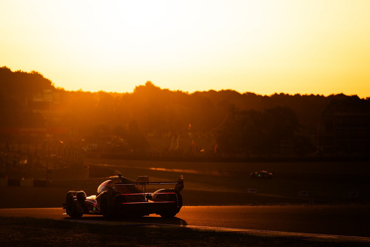 Silhouetted GRM-001 driving on track at sunset, glowing under golden light.