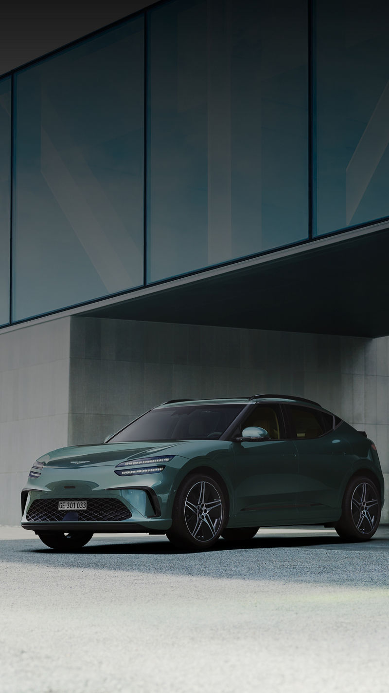  Vor dem Hintergrund des modernen Gebäudes steht links ein GV60 in Tromsø-Grün und rechts ein GV60 in Uyuni-Weiß.