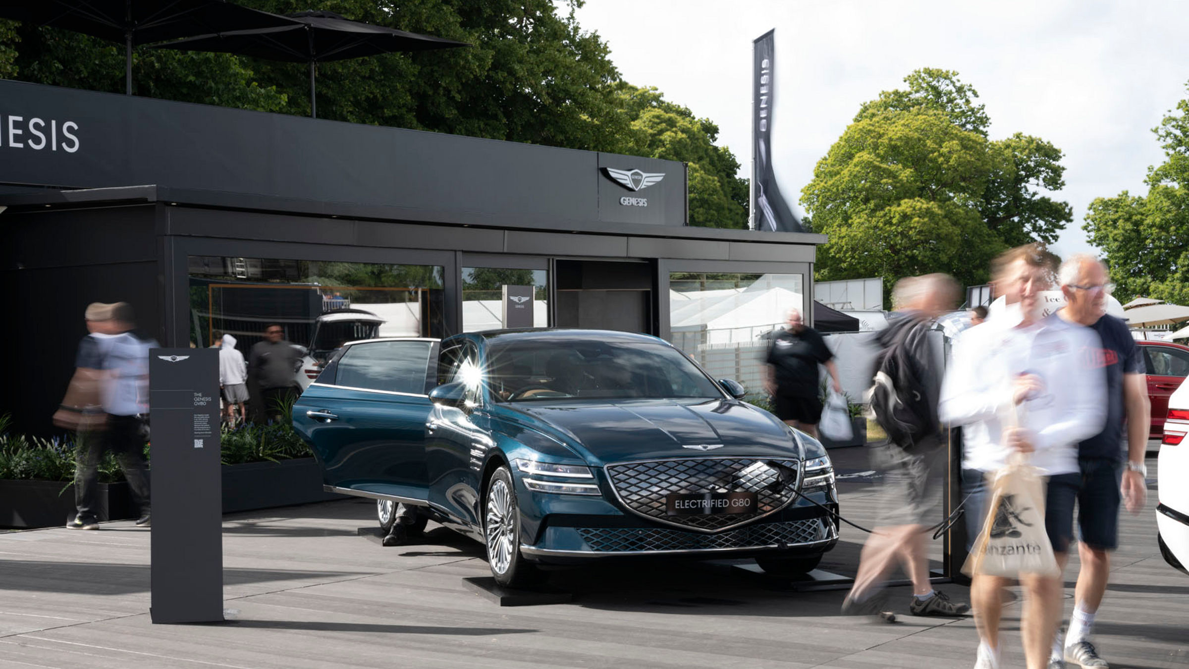 Blue Genesis G80 in front of a building at an outdoor event