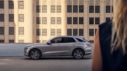 Back of a woman with a Genesis car in front of a house wall in the background
