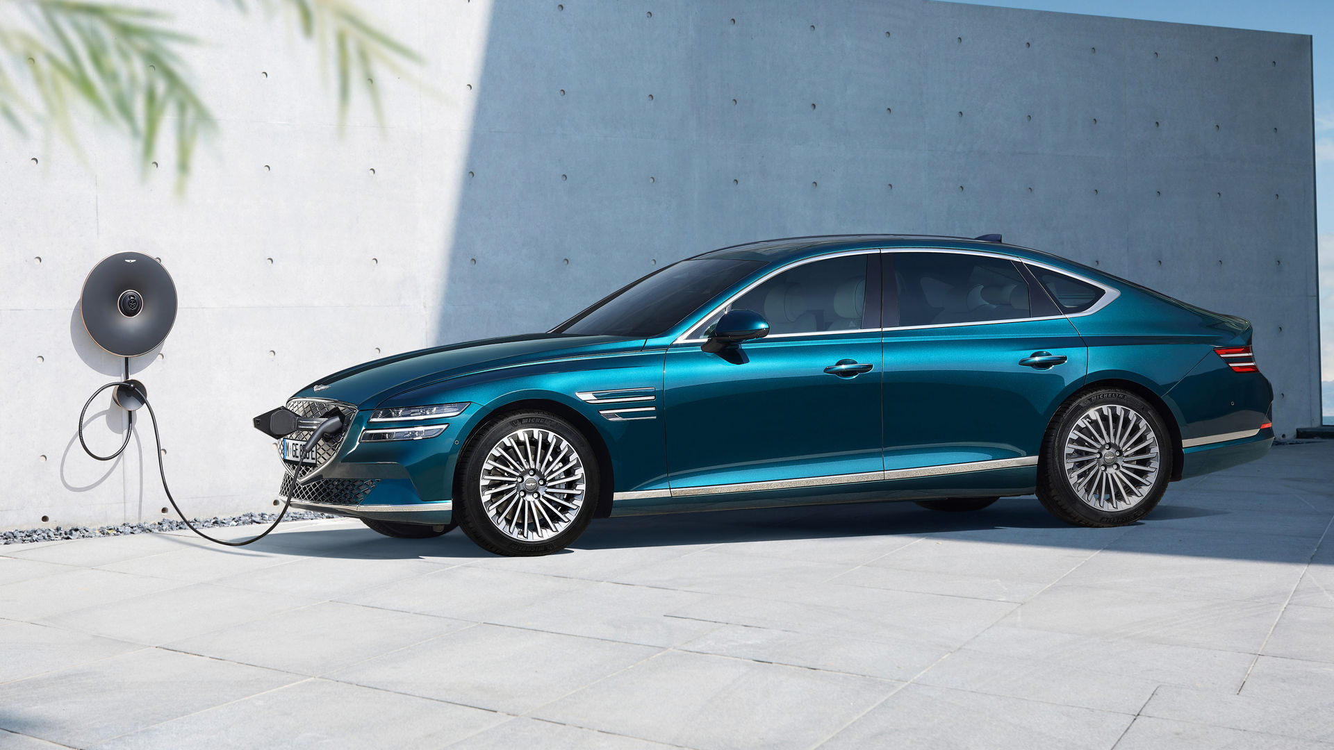 An electric Genesis G80 in blue charges at a charging station on a wall