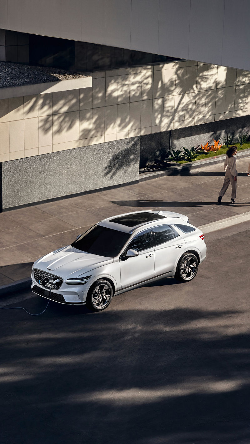 Genesis GV60 in white is parked at a charging station in the city