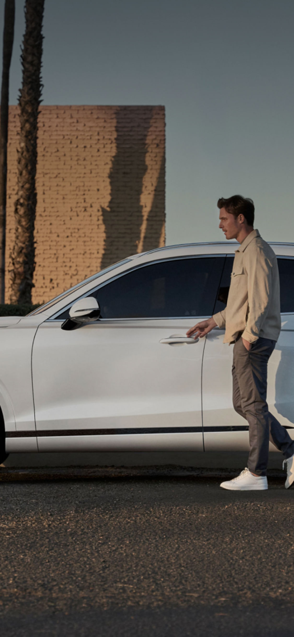 A man walking to open the door of his white SUV