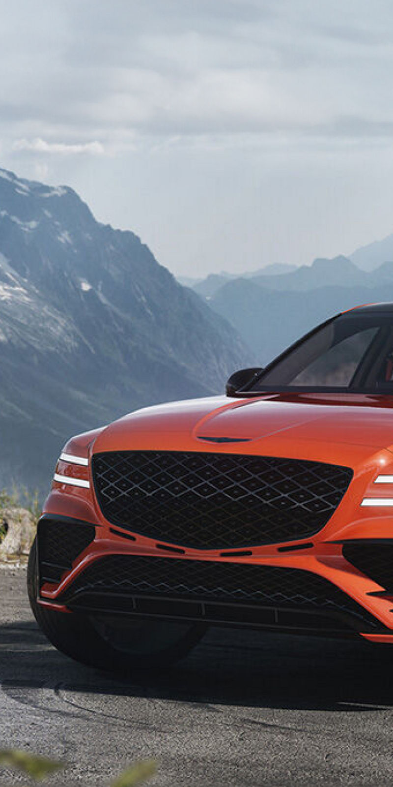 Front view of the Genesis Magma in vibrant orange with a mountain backdrop