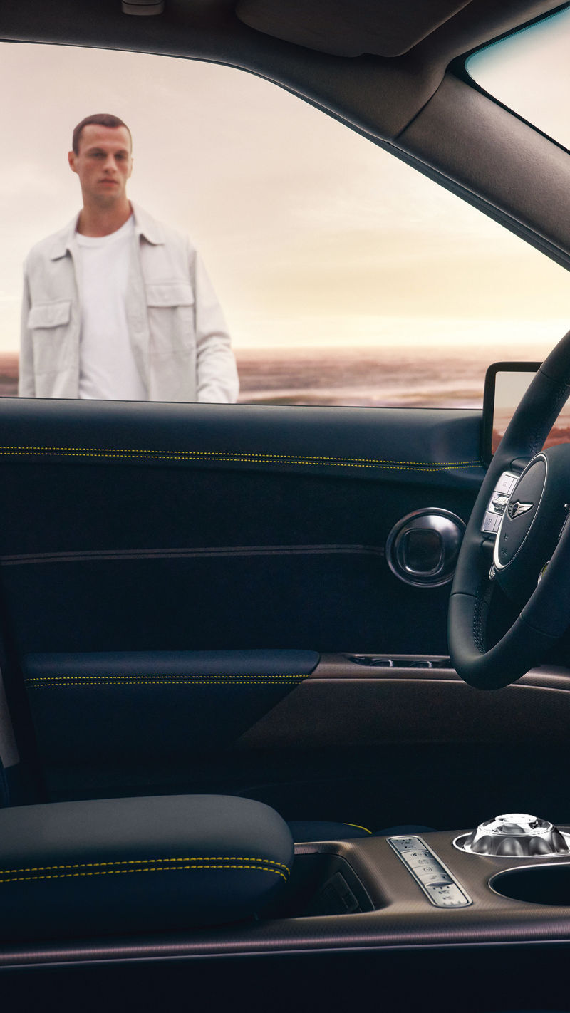 Man looks through the window at the driver's seat of the Genesis GV60