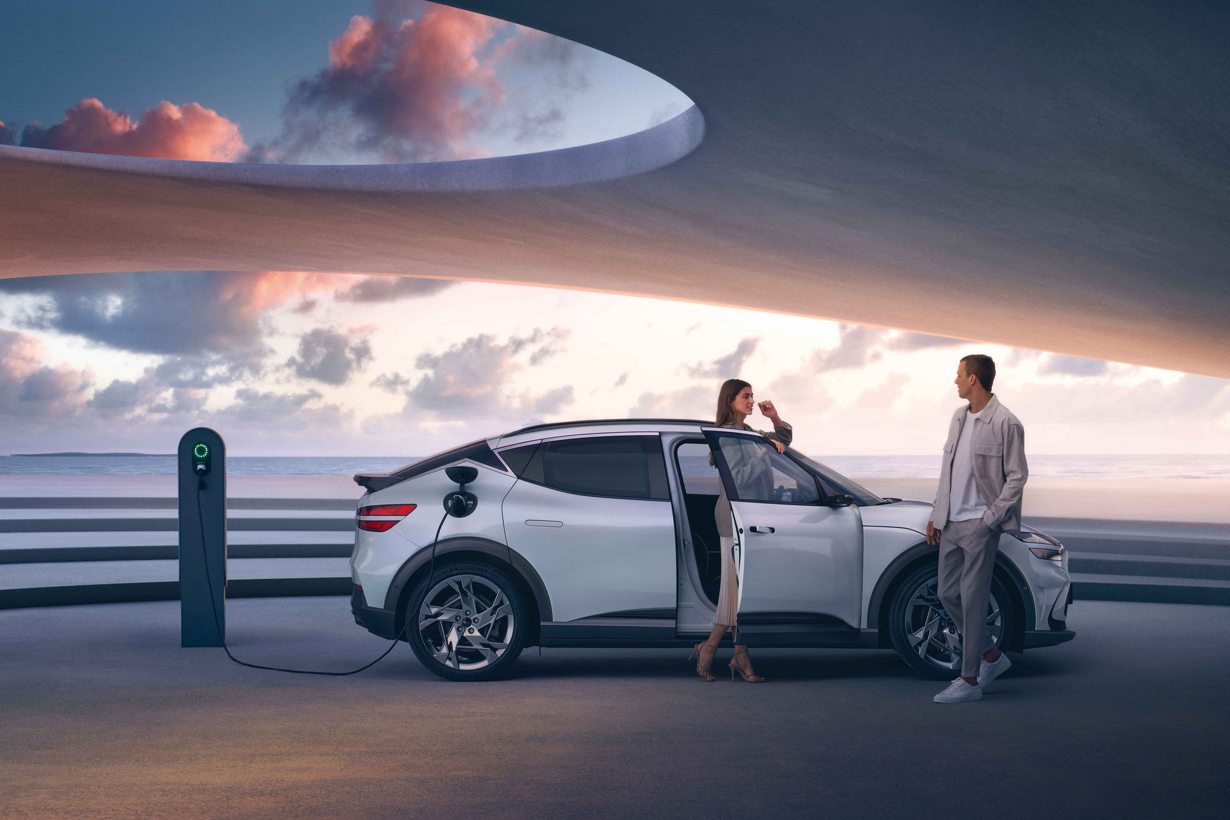 Man and woman next to an electric car parked at a charging station by the sea