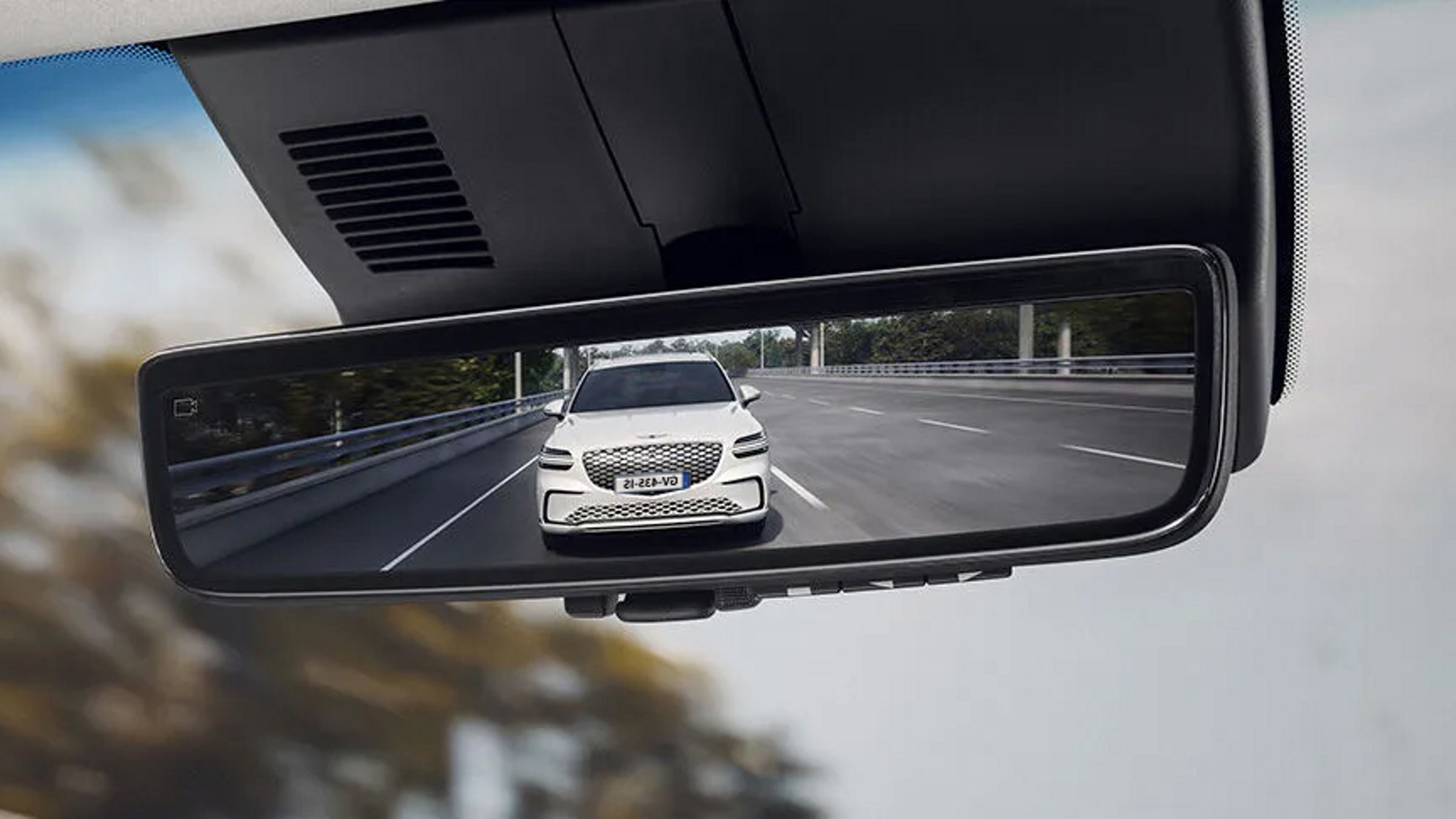 In the vehicle's rearview mirror, another vehicle from behind can be seen.