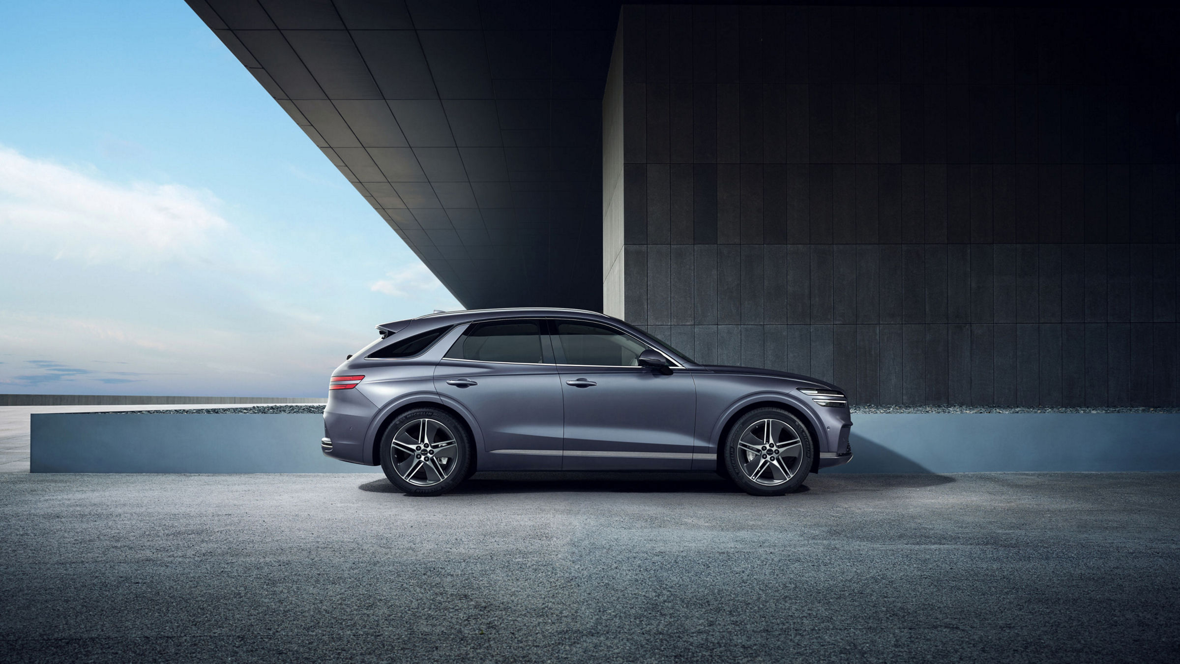 Vista lateral del exterior del SUV eléctrico de lujo Genesis Electrified GV70, en la que se aprecia su diseño.