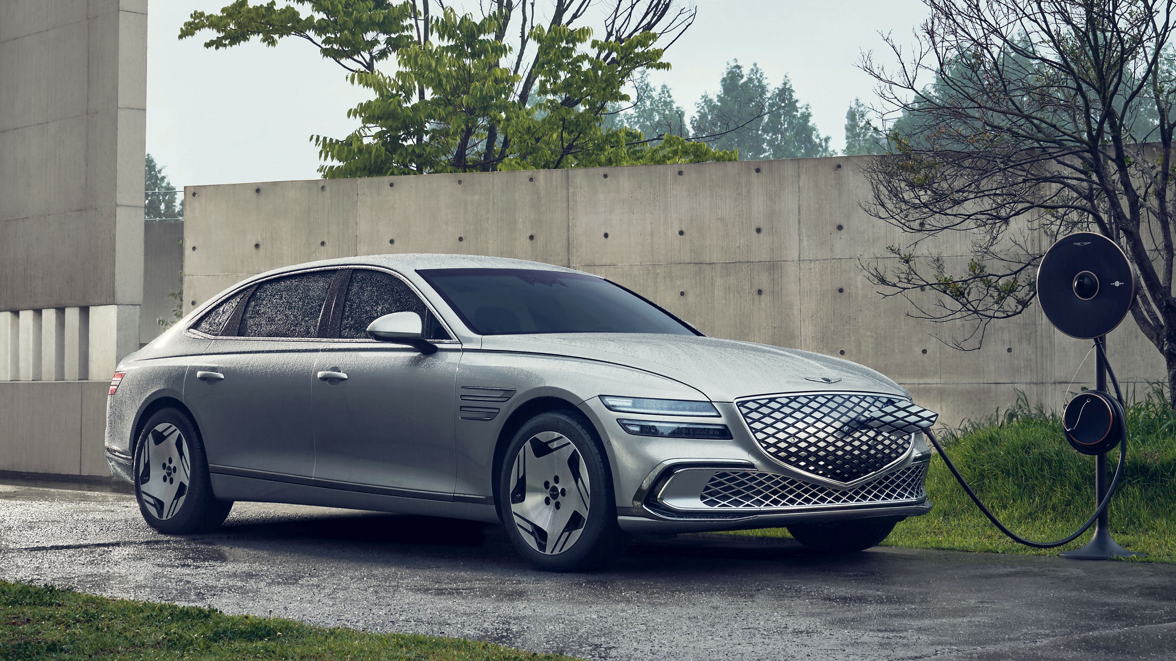 An Electrified G80 is parked at an outdoor charging station. It is connected to the charger and charging.