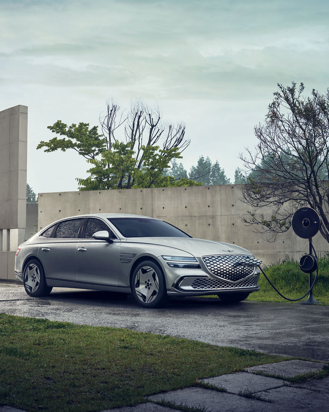 An Electrified G80 is parked at an outdoor charging station. It is connected to the charger and charging.