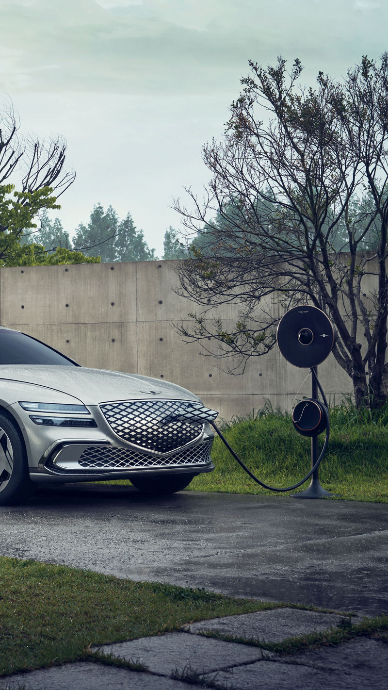 An Electrified G80 is parked at an outdoor charging station. It is connected to the charger and charging.