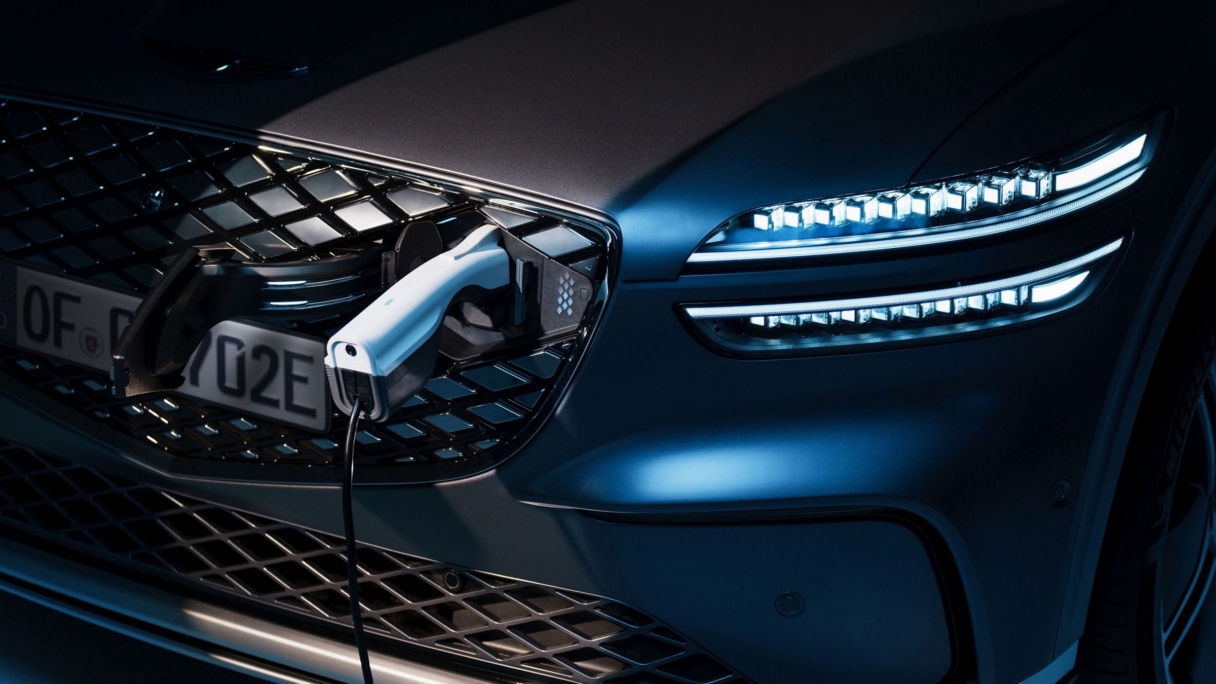 Se conecta un cargador al puerto de carga delantero de un vehículo eléctrico Genesis.