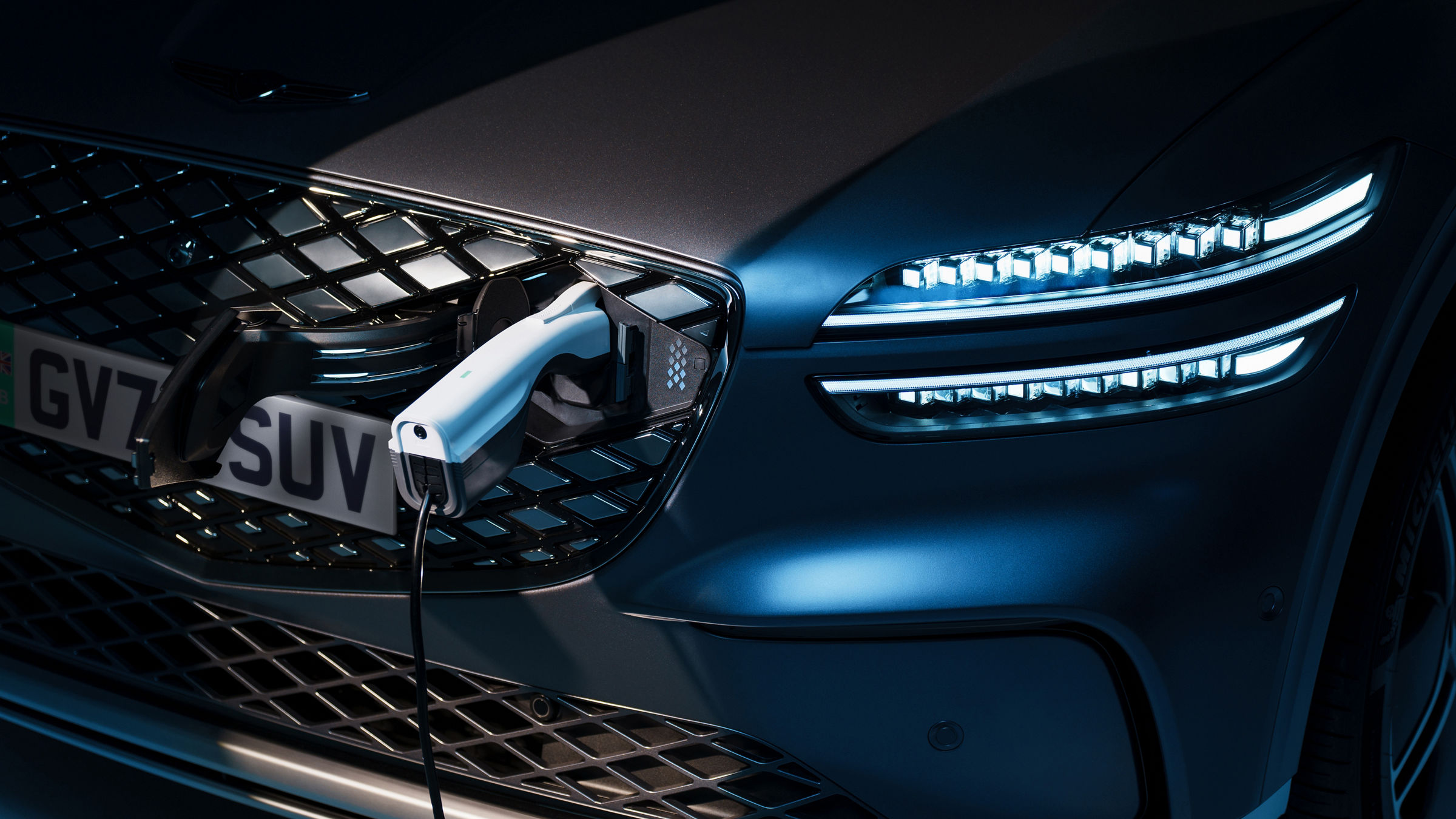 A charger is plugged into the front charging port of a Genesis electric vehicle.