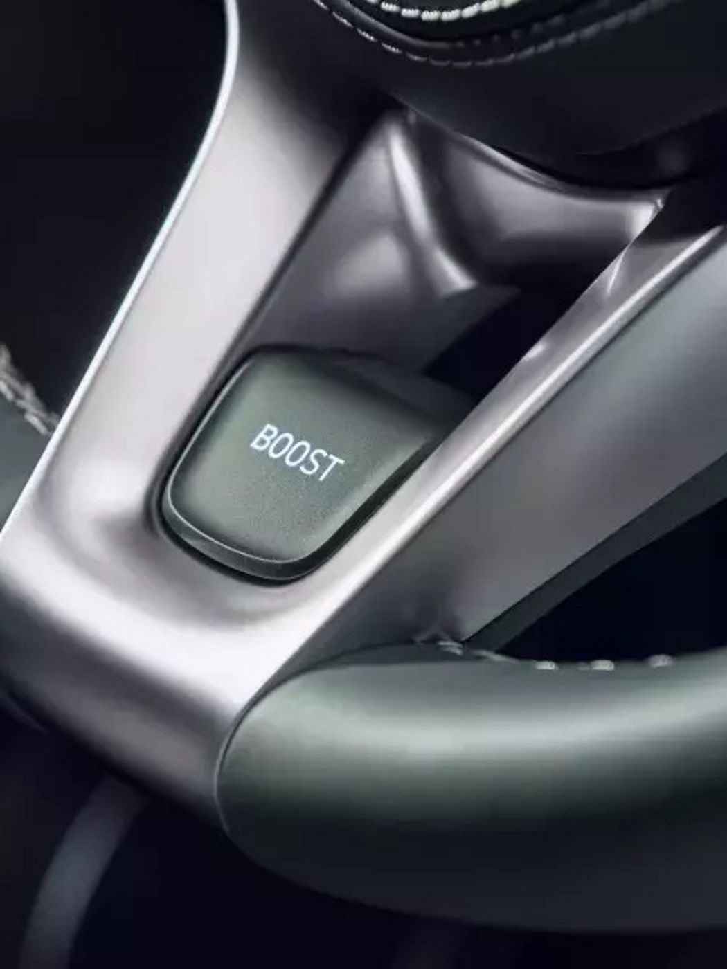 A close-up of the "BOOST" button on the Genesis GV70's steering wheel, designed for dynamic driving performance.