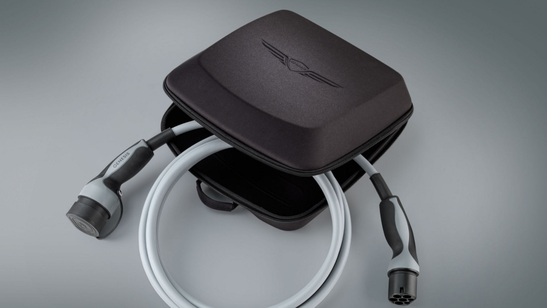 A Genesis Electrified G80 charging cable in a compact carrying case with the Genesis logo on the lid.