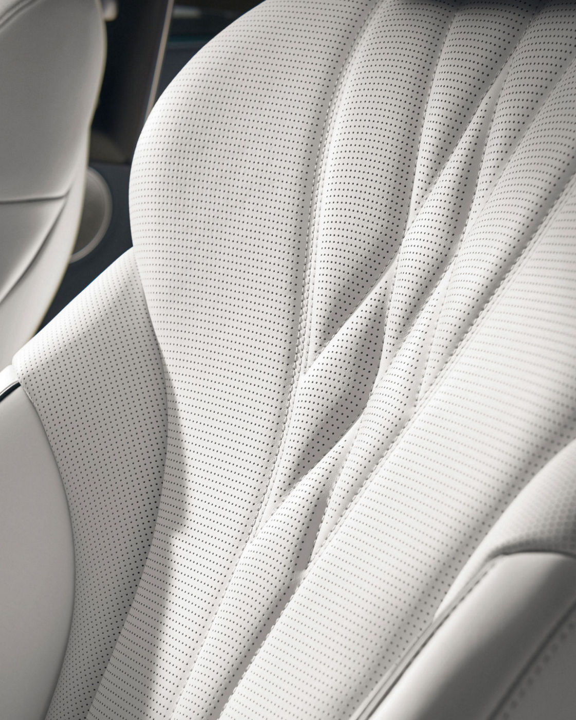 A white, perforated leather seat in the Electrified G80 with intricate stitching and ergonomic design.