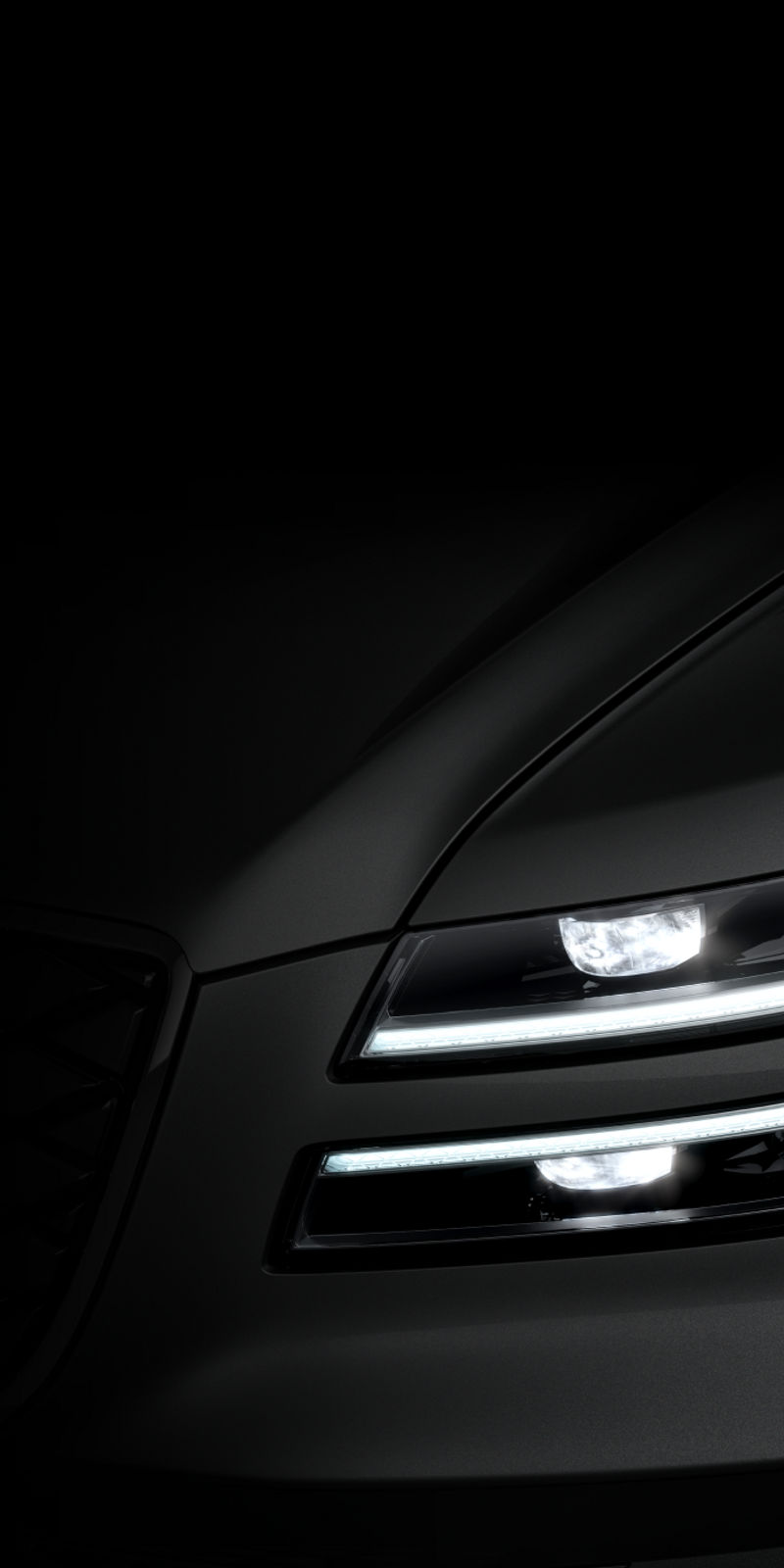 A close-up of the Electrified G80's signature quad headlamps glowing brightly at night.