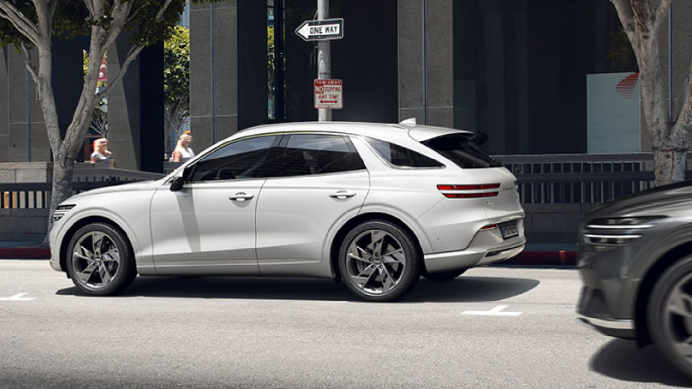 The Electrified Genesis GV70 parked on a sunny city street, highlighting its elegant white exterior and premium styling.