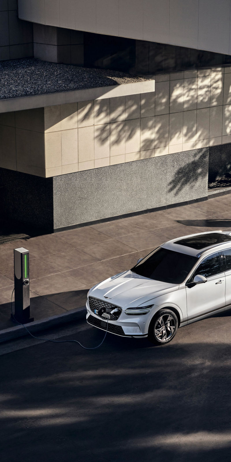 An aerial view of the Genesis Electrified GV70 parked at a public charging station